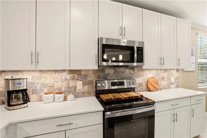 Kitchen featuring stainless steel appliances, white cabinets, and tasteful backsplash