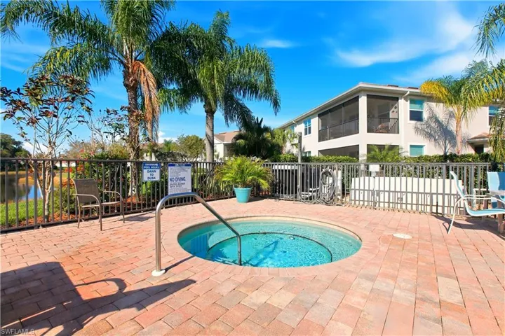 View of pool with a hot tub, patio surround, a water view, and a sunroom