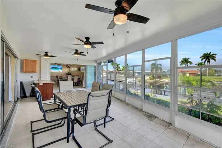 Sunroom featuring outdoor dining space, a water view, ceiling fan, and tile patterned flooring