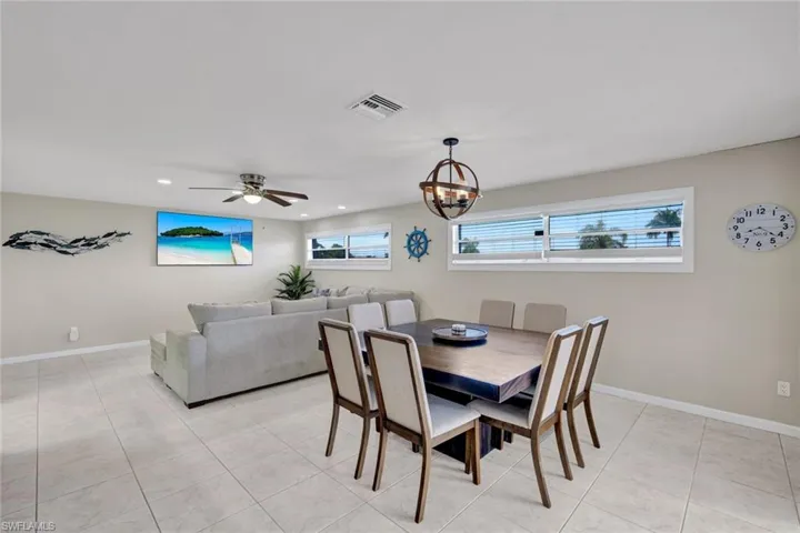Dining area with light tile patterned floors, a chandelier, a ceiling fan, and recessed lighting