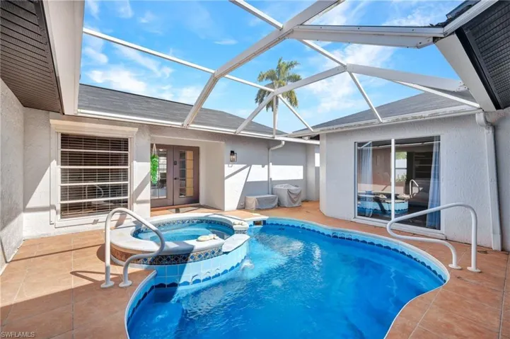 View of swimming pool featuring a sunroom, a patio, a pool with connected hot tub, a lanai, and french doors