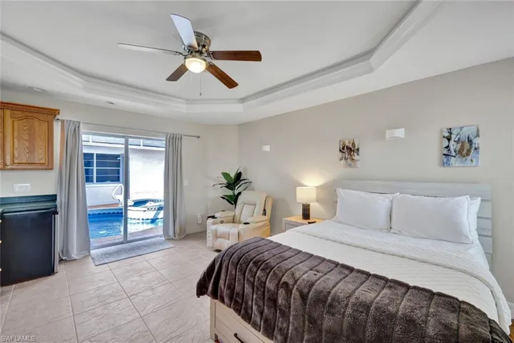 Bedroom with a tray ceiling, access to outside, and ceiling fan