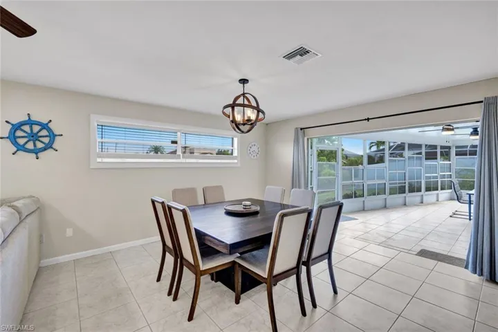 Dining room with ceiling fan, light tile patterned flooring, and a sunroom