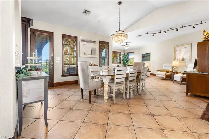Dining space with lofted ceiling, light tile patterned floors, suspended lighting, and healthy amount of natural light