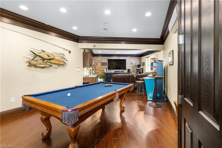 Family room featuring wood finished floors, billiards table, recessed lighting, crown molding, and bar area