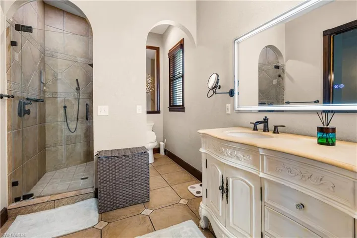 Master bath with vanity, a shower stall, light tile patterned flooring, and a textured wall