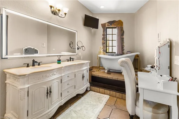Master Bathroom featuring double vanity, a freestanding bath, and light tile patterned floors