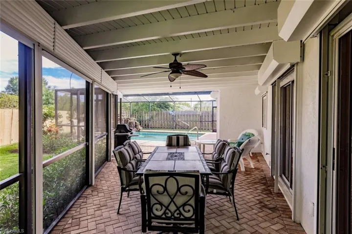 Sunroom featuring ceiling fan, outdoor dining area, beam ceiling, and a patio