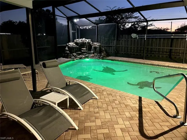 Pool at dusk featuring glass enclosure, a patio, and a sunroom
