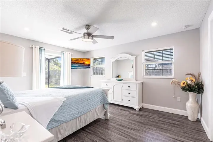 Bedroom featuring dark wood-style flooring, multiple windows, ceiling fan, and a textured ceiling
