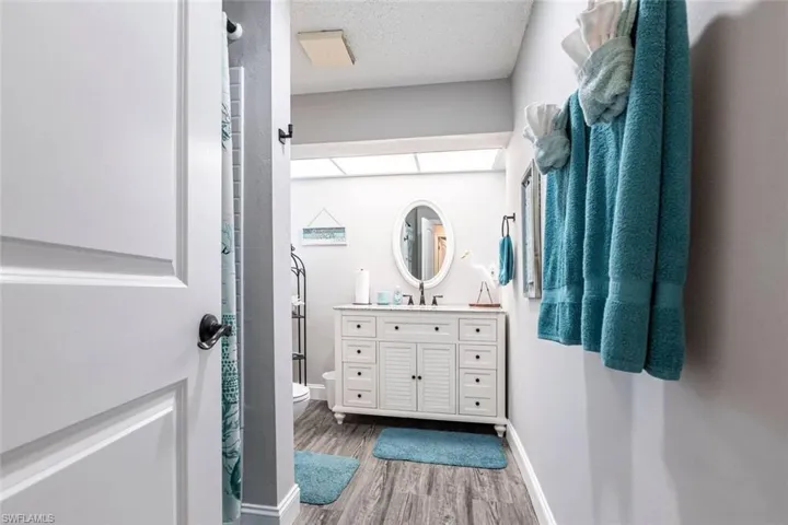 Full bathroom featuring curtained shower, vanity, light wood-style flooring, and a textured ceiling