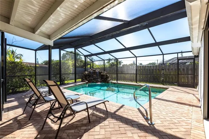 View of pool featuring a sunroom, patio surround, a fenced backyard, and a lanai