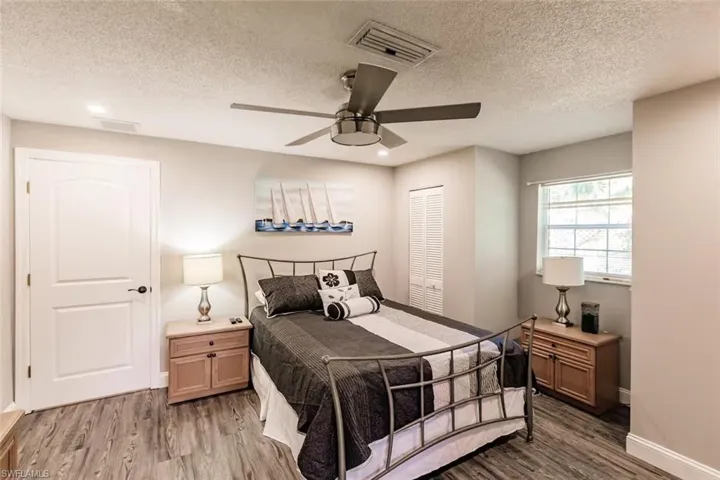 Bedroom with light wood-style floors, ceiling fan, and a textured ceiling