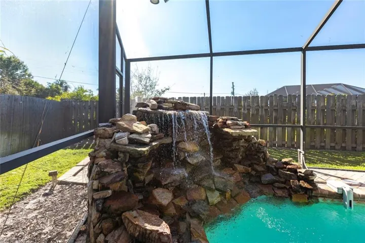 Fenced backyard featuring a sunroom and a garden pond
