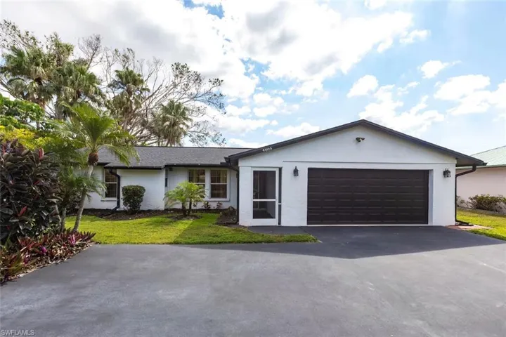Single story home featuring stucco siding, a front lawn, driveway, and a garage