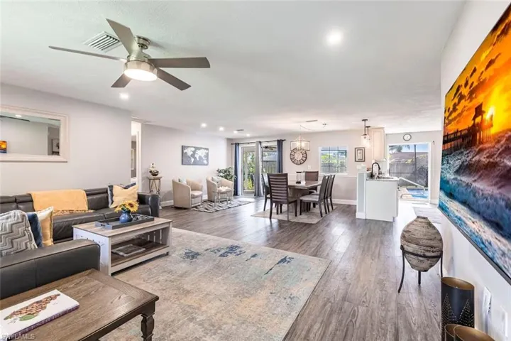Living room with dark wood-style floors, ceiling fan, and recessed lighting