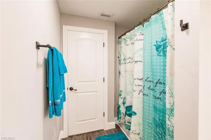 Full bathroom with a shower with shower curtain, a textured ceiling, and wood finished floors