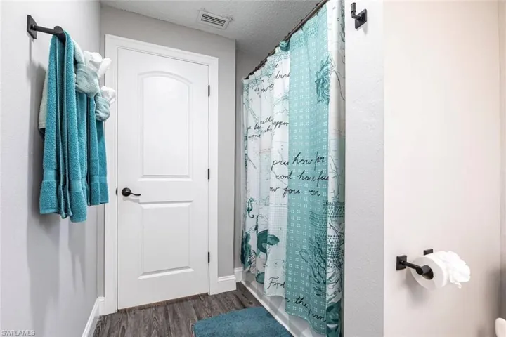 Bathroom with a textured ceiling, dark wood-type flooring, and shower / bath combo