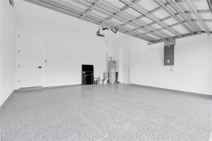 Garage featuring electric panel, electric water heater, and a garage door opener