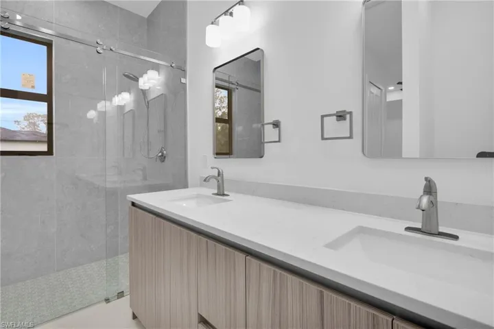 Bathroom featuring double vanity and a stall shower