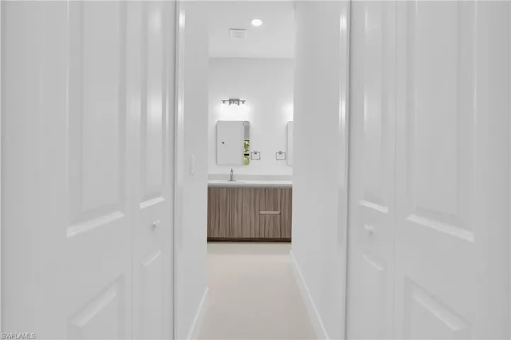 Hallway with light tile patterned floors and a sink