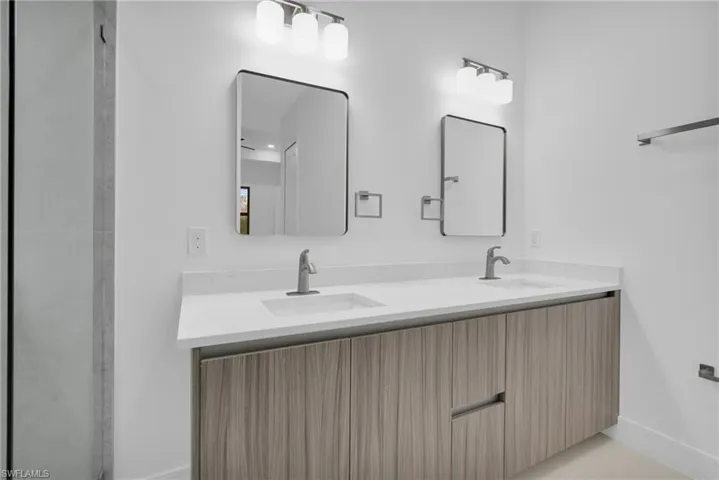 Bathroom with double vanity and baseboards