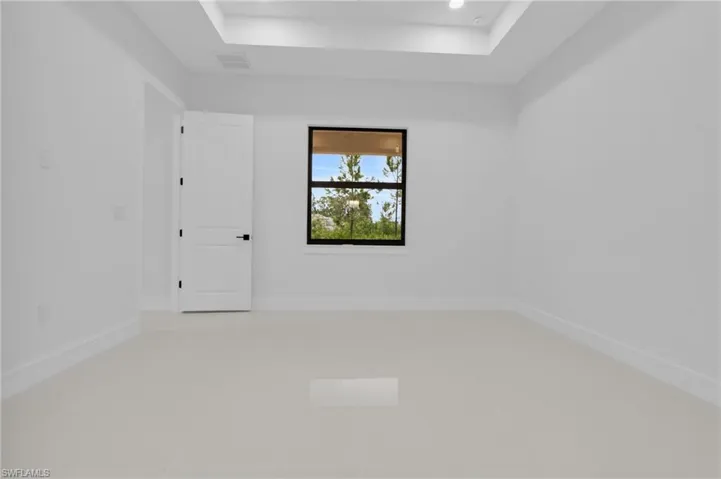 Tiled empty room with a raised ceiling and baseboards