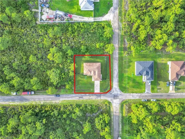 Aerial view of property and surrounding area featuring property parcel outlined and a tree filled landscape