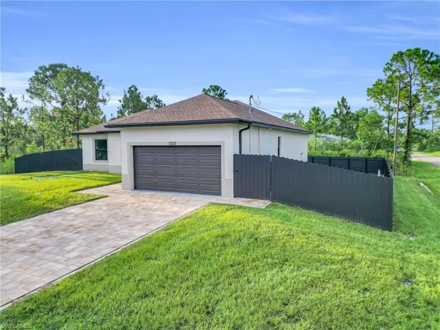 View of side of home with stucco siding, decorative driveway, a garage, and a shingled roof