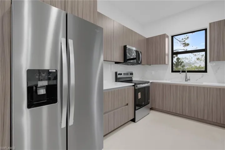 Kitchen featuring stainless steel appliances, modern cabinets, decorative backsplash, and light stone counters