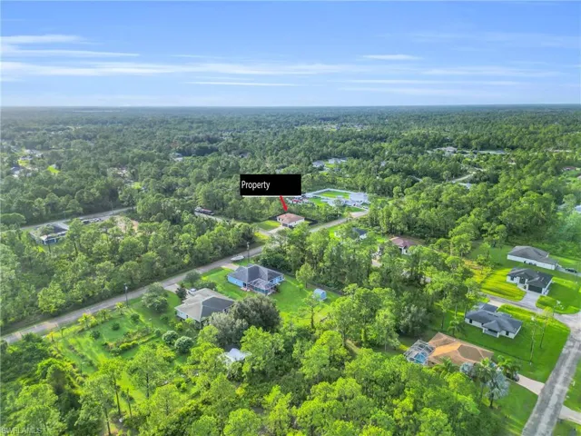 Aerial view of property and surrounding area with a heavily wooded area