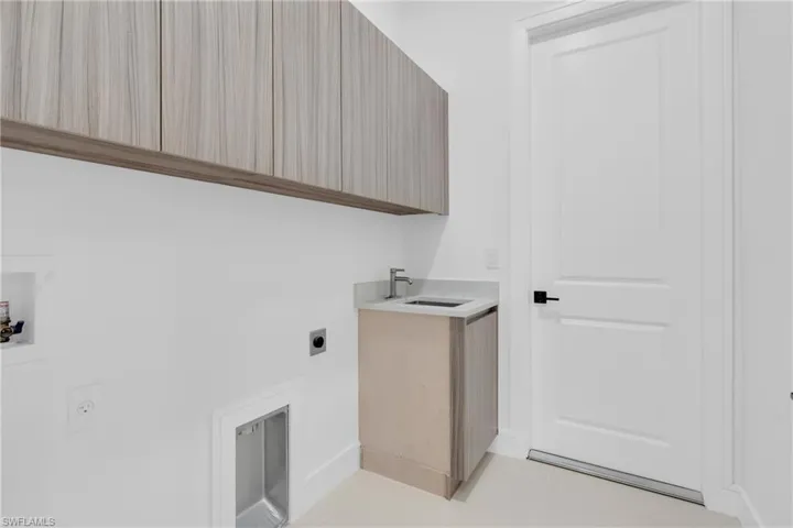 Laundry area with hookup for an electric dryer, light tile patterned flooring, washer hookup, and cabinet space