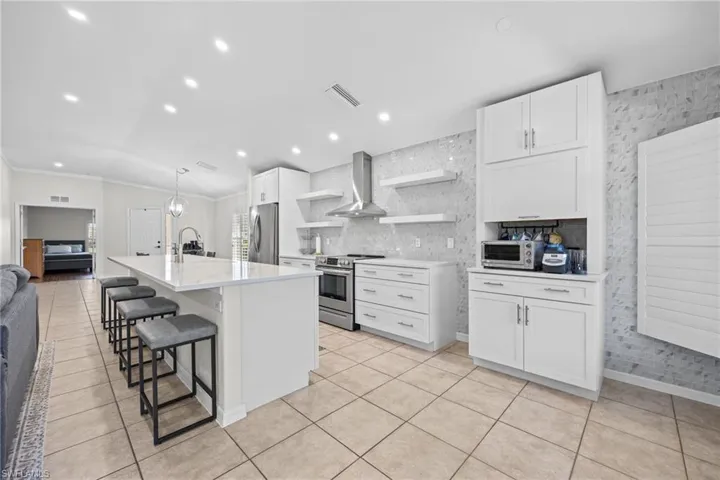 Spacious kitchen with white cabinetry, stainless steel appliances, a large center island, and tile flooring