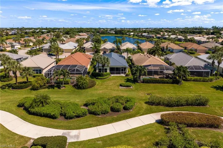 Expansive green spaces with mature landscaping, a paved pathway, and a distant water feature