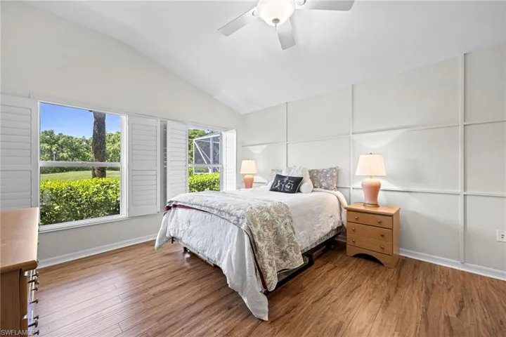 Vaulted ceiling with a ceiling fan, wood-finish flooring, white panel accent wall, and plantation shutters