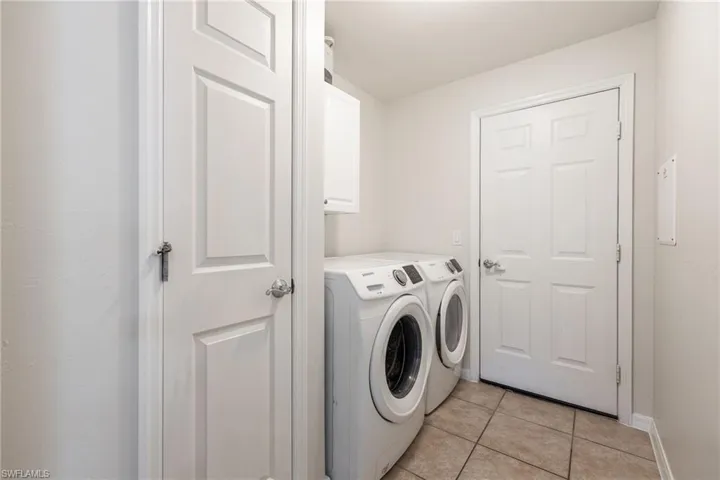 Dedicated laundry area featuring ceramic tile flooring, a built-in upper cabinet, and panel doors