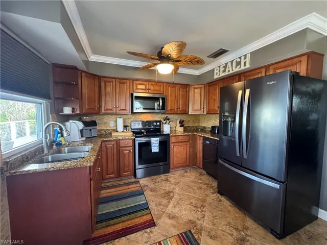 Kitchen featuring sink, ceiling fan, ornamental molding, tasteful backsplash, and stainless steel appliances
