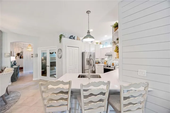 Kitchen with appliances with stainless steel finishes, arched walkways, a peninsula, light tile patterned flooring, and light countertops