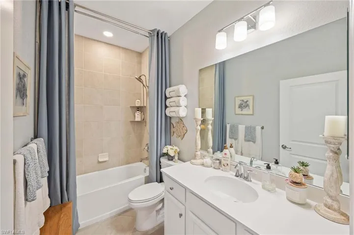 Full bath with shower / bath combo with shower curtain, vanity, and tile patterned flooring