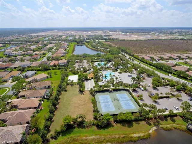 Aerial view of property and surrounding area with a nearby body of water and a pool area