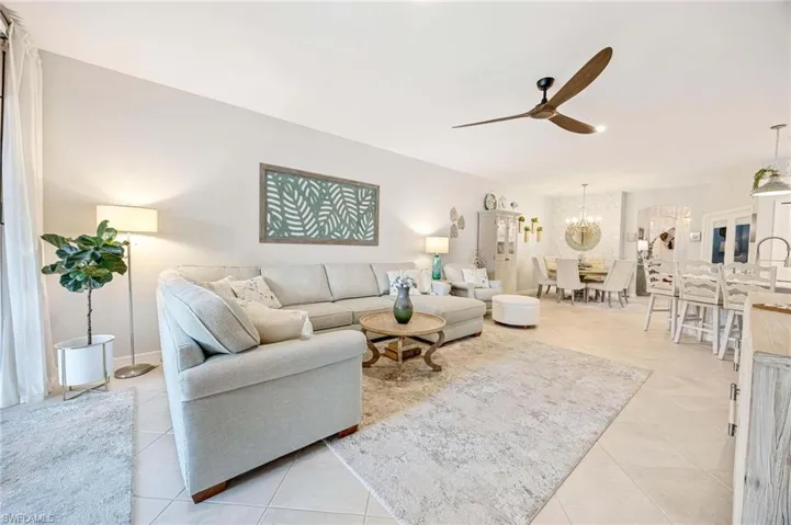 Living room featuring ceiling fan, light tile patterned flooring, and a chandelier