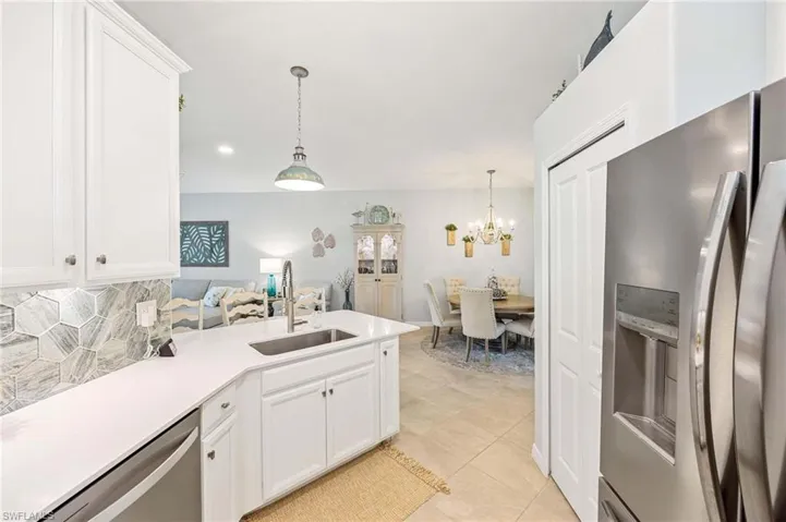 Kitchen with appliances with stainless steel finishes, backsplash, a chandelier, a peninsula, and light countertops