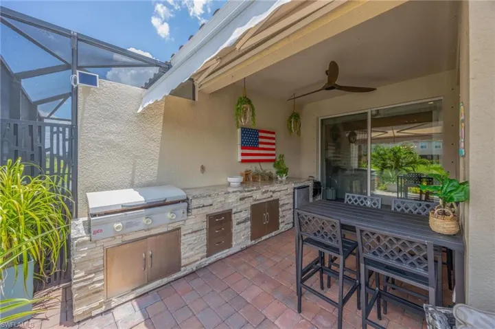 View of patio / terrace with exterior kitchen, ceiling fan, and glass enclosure