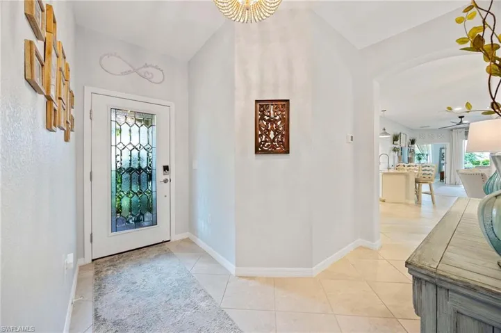 Entryway with healthy amount of natural light, a chandelier, and light tile patterned floors