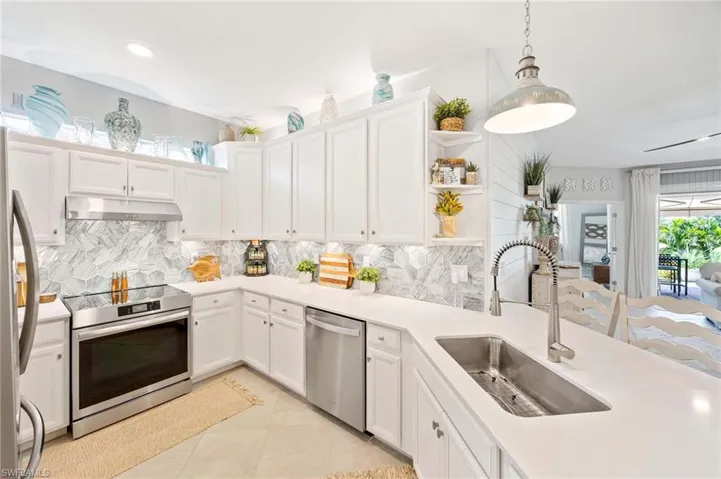 Kitchen with stainless steel appliances, under cabinet range hood, backsplash, and white cabinets