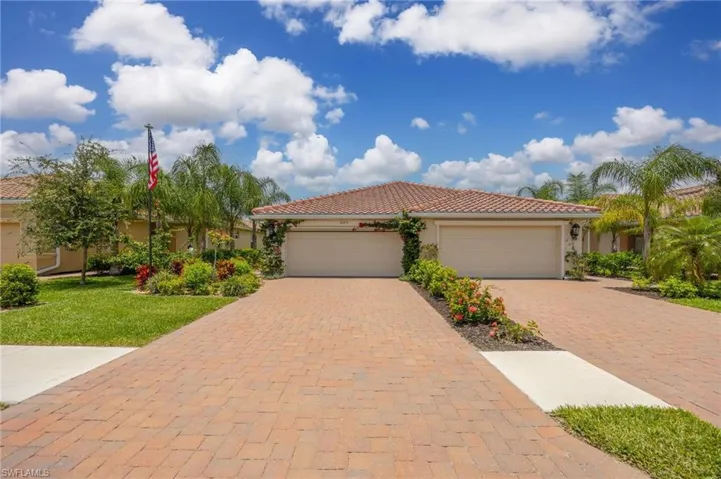 Mediterranean / spanish house with stucco siding, decorative driveway, a garage, a front yard, and a tiled roof