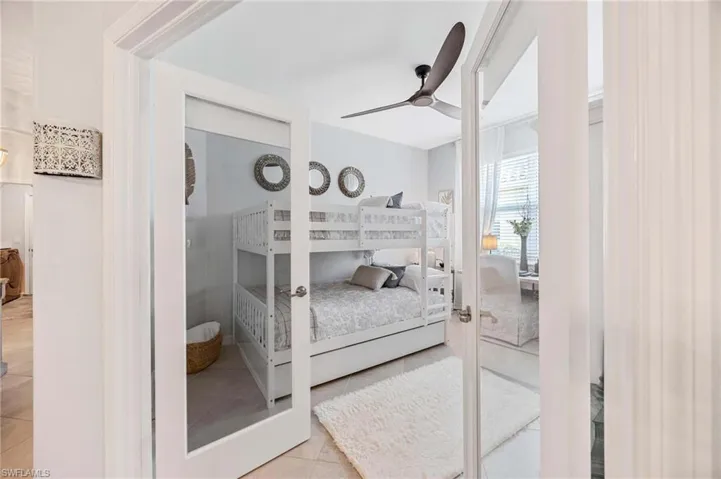 Tiled bedroom with ceiling fan and french doors
