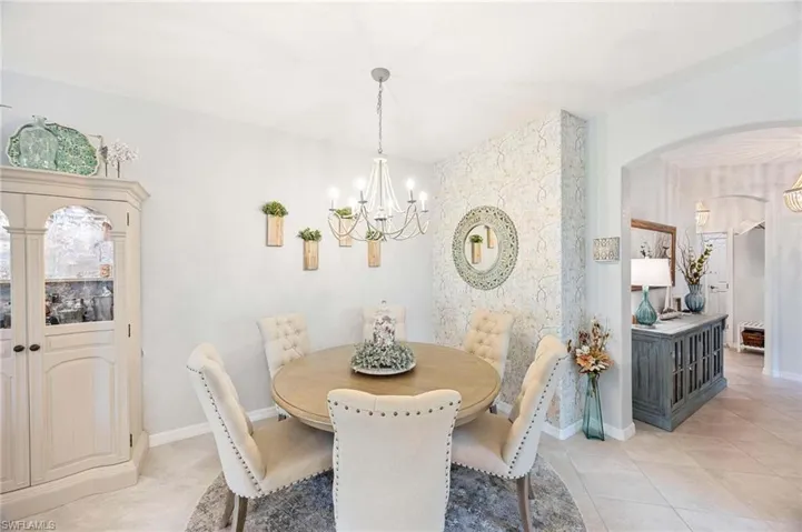 Dining area featuring arched walkways, a chandelier, and light tile patterned floors