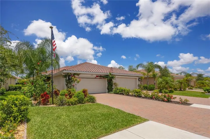Mediterranean / spanish home featuring stucco siding, decorative driveway, a tiled roof, a front lawn, and a garage