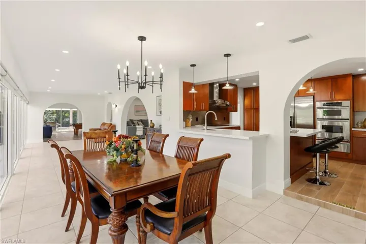 Dining room with arched walkways, recessed lighting, a chandelier, and light tile patterned floors